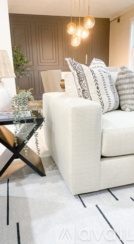 A white couch with a black and white pillow is in the foreground of a room.