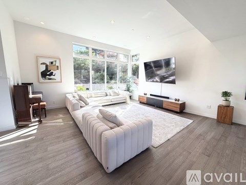 A modern living room with a large white sofa and a flat screen TV mounted on the wall.