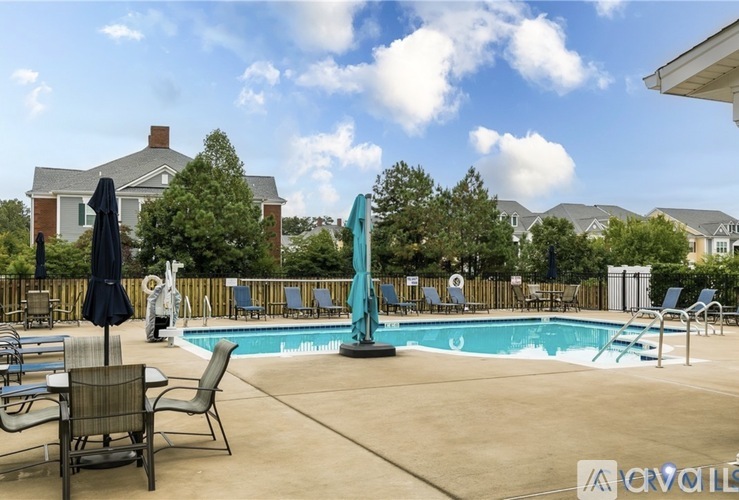 A pool with chairs and umbrellas in front of a house.