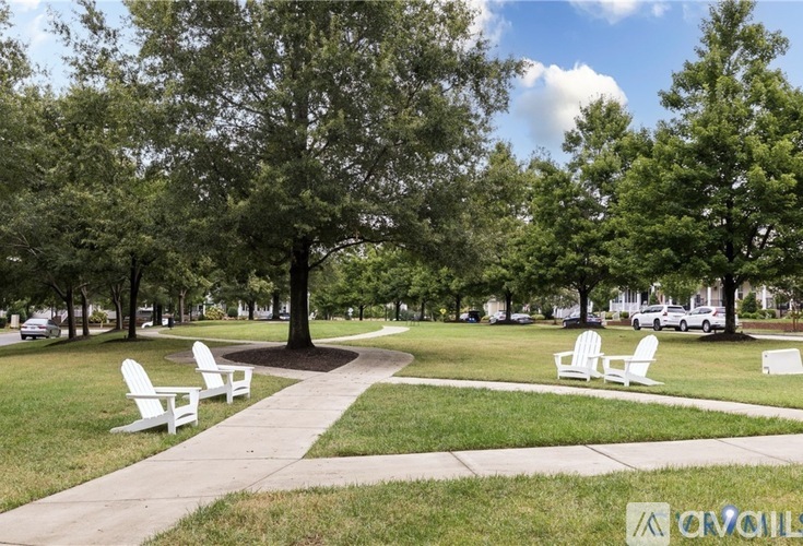 A park with white chairs and trees.