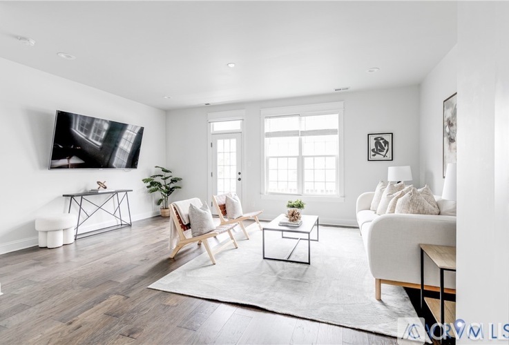 A living room with a white couch, a wooden chair, and a coffee table.