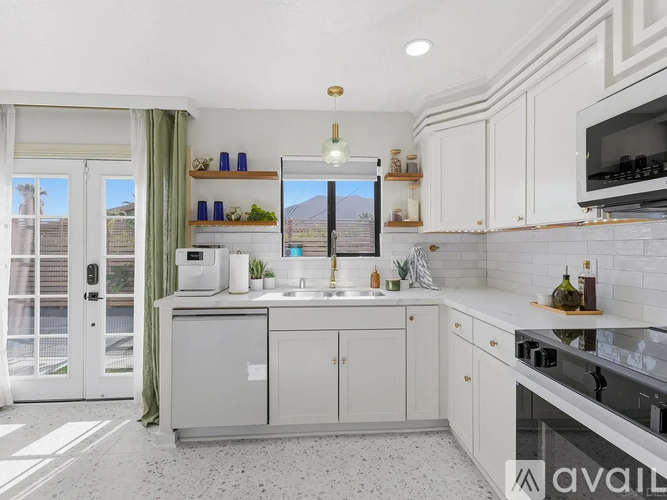 A kitchen with white cabinets and a large window overlooking a balcony.