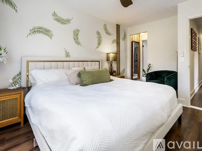 A bedroom with a white bed and a green pillow.