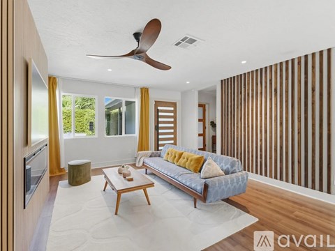 A living room with a blue couch and a wooden wall.