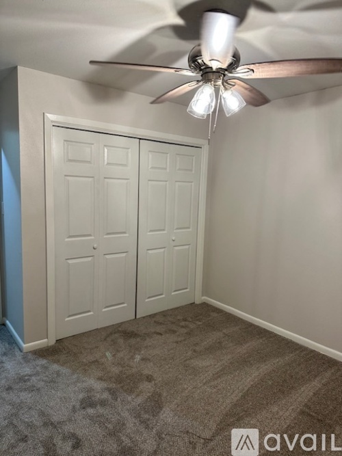 A room with a ceiling fan and two doors.