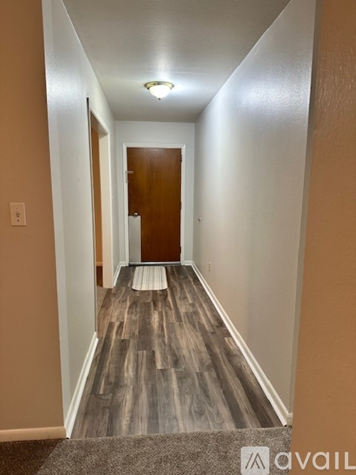A hallway with a brown door and wood flooring.