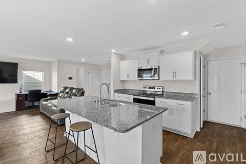 A modern kitchen with granite countertops and white cabinets.