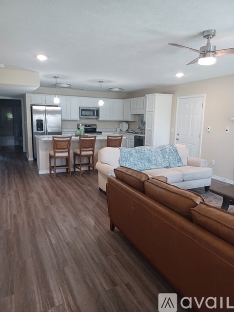 A living room with a brown couch and a kitchen in the background.