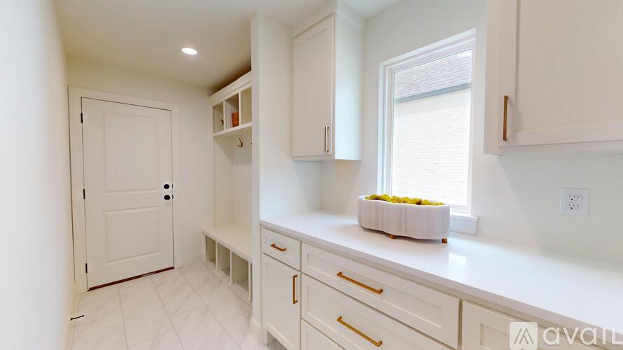A kitchen with white cabinets and a bowl of fruit on the counter.
