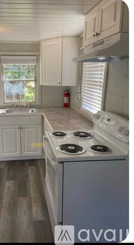 A kitchen with a white stove top oven and white cabinets.