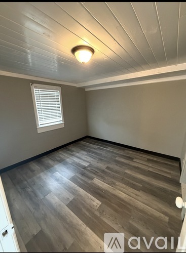 A room with wooden flooring and a window with blinds.