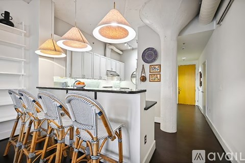 A kitchen with white walls and a black counter top.