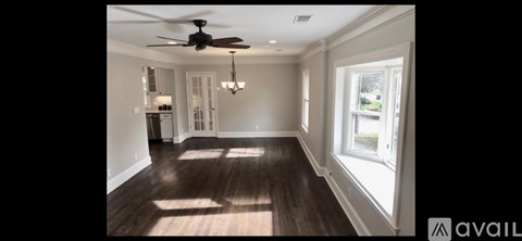 A spacious room with a ceiling fan and a chandelier.