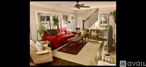 A living room with a red couch and a fan.