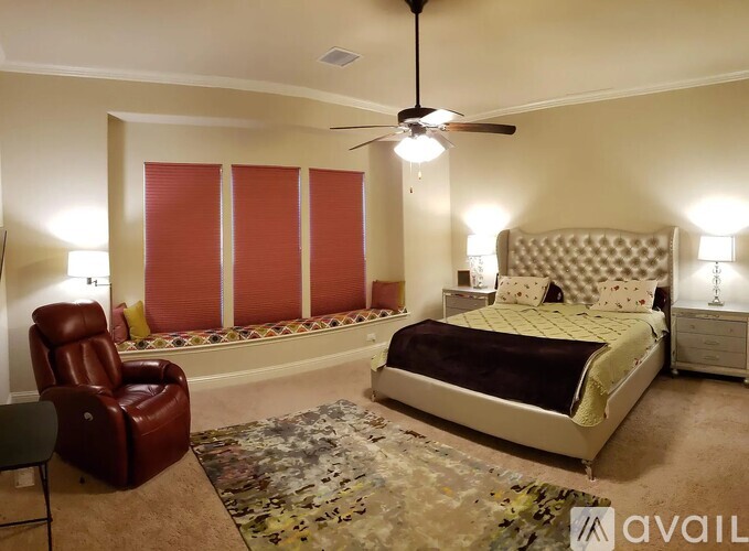 A bedroom with a bed, chair, and a rug.