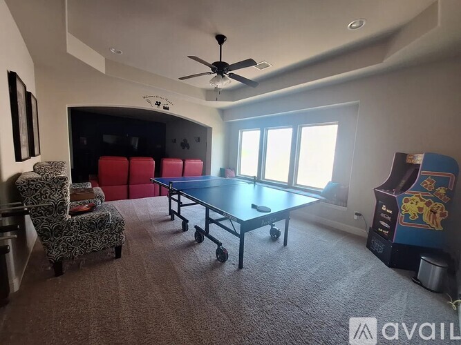 A room with a ceiling fan, a pool table, and a chair.