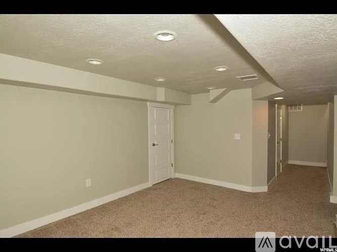 A room with a carpeted floor and a door on the left side.