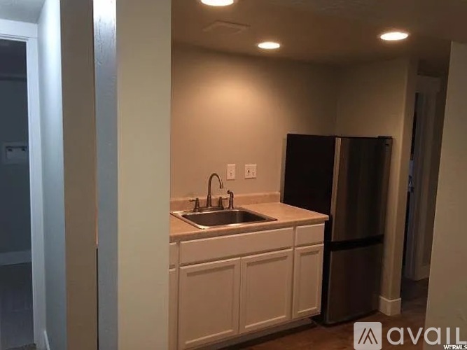A kitchen with white cabinets and a black refrigerator.