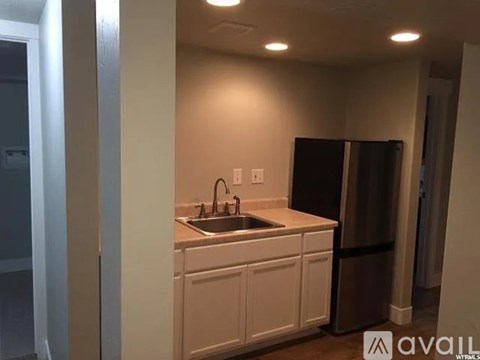 A kitchen with white cabinets and a black refrigerator.