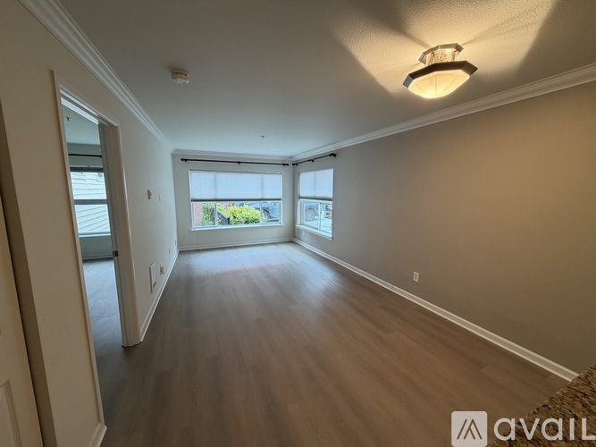 A spacious room with wooden flooring and a large window.