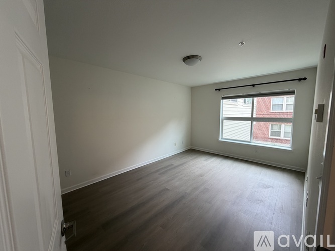 A room with wooden floors and a window with blinds.