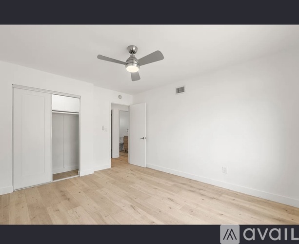 A room with a ceiling fan and wooden flooring.