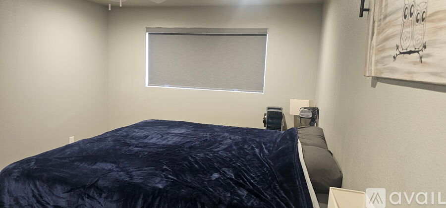 A bedroom with a bed covered in a blue comforter.