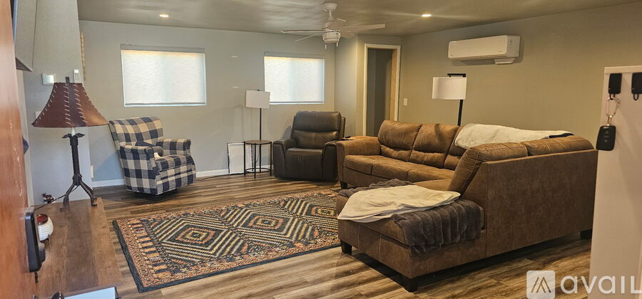 A living room with a brown couch and a rug.