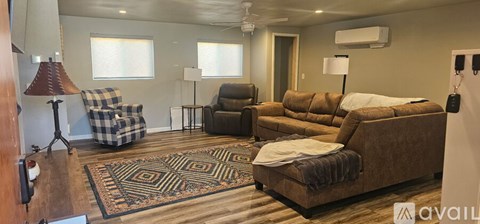 A living room with a brown couch and a rug.