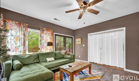 A living room with a green couch and a ceiling fan.