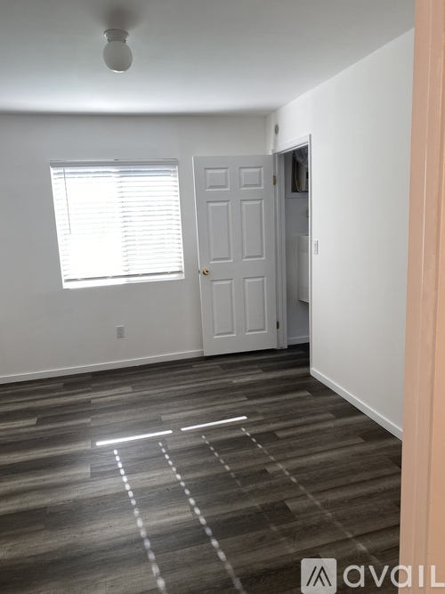 A room with a door, window, and wooden floor.