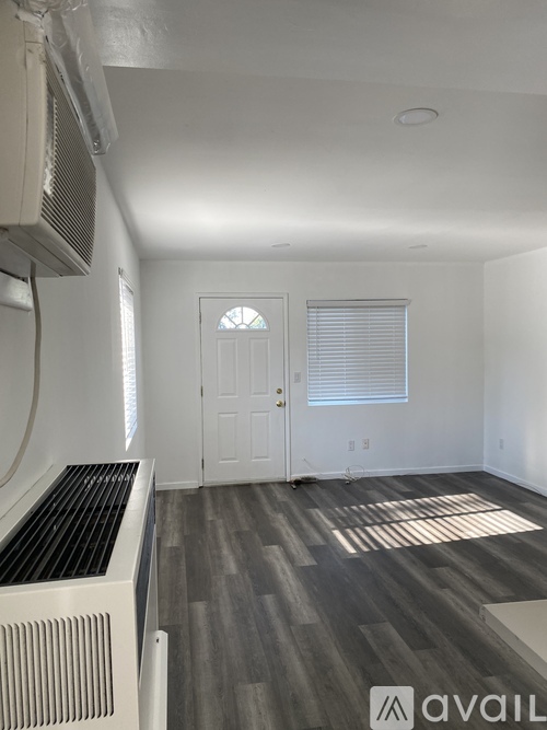 A room with a white door, a window with blinds, and a wall-mounted air conditioner.