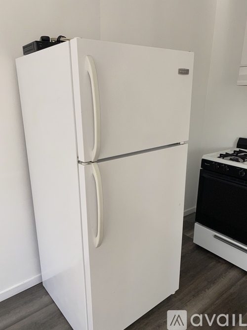 A white fridge in a kitchen with a stove in the background.