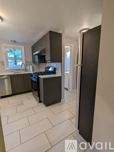 A kitchen with a black refrigerator and white tiled flooring.
