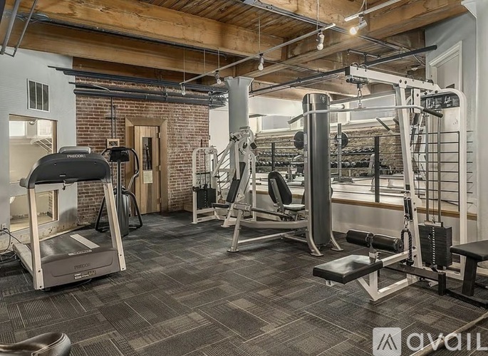 A gym with a variety of equipment including a treadmill, weights, and a bench press.