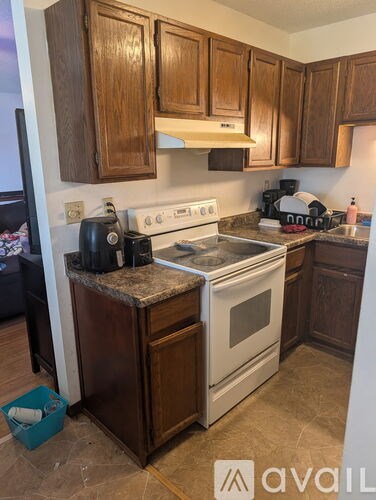 A kitchen with a white stove and wooden cabinets.