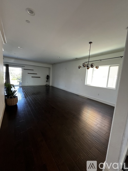 A large empty room with wooden floors and a hanging light fixture.