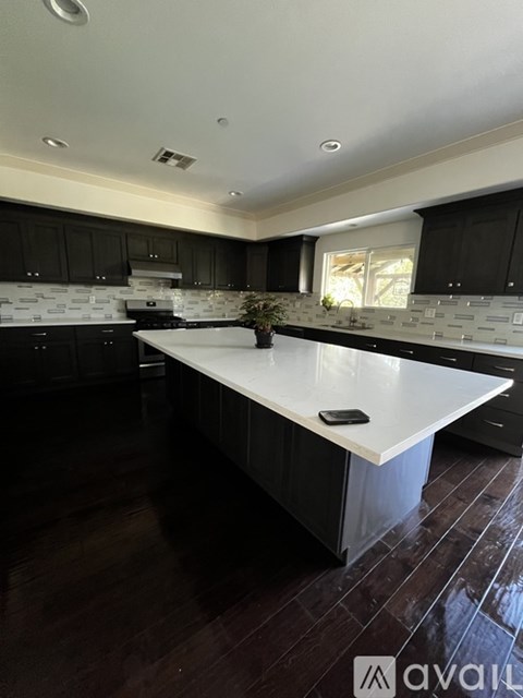 A kitchen with a white countertop and black cabinets.