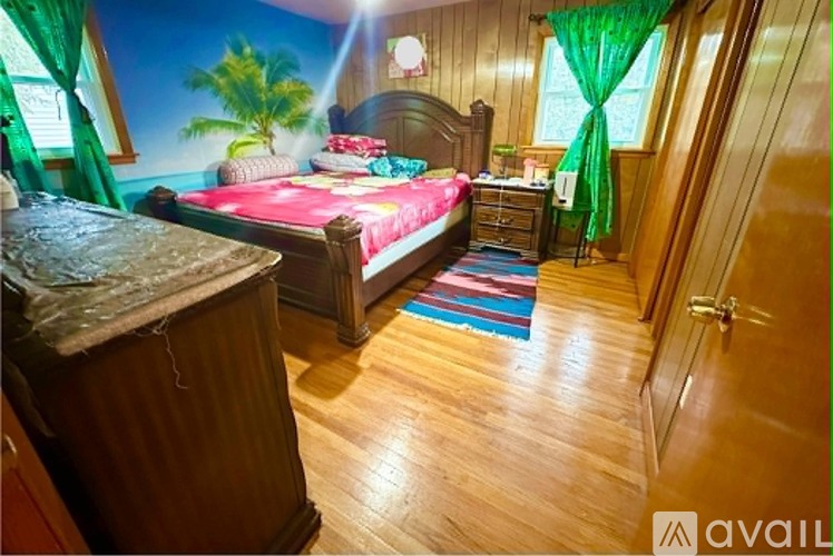 A bedroom with a bed, nightstand, and a wooden floor.