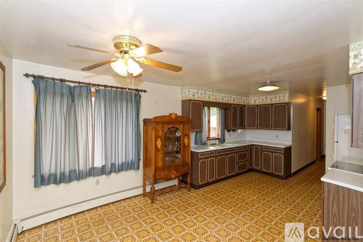 A living room with a ceiling fan and patterned carpet.