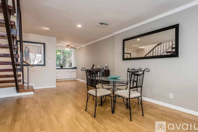A dining room with a wooden floor and a large mirror on the wall.