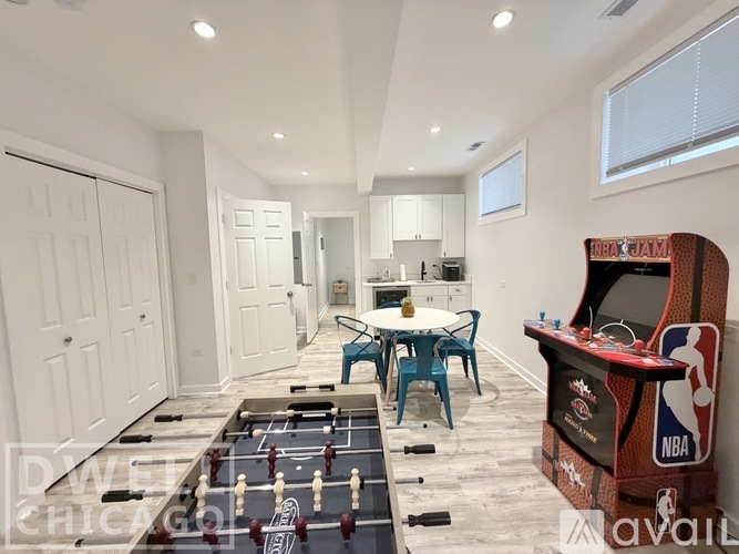 A game room with a foosball table and a basketball hoop.