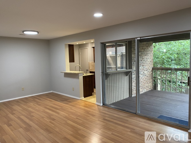 A room with wooden flooring and a sliding glass door leading to a balcony.