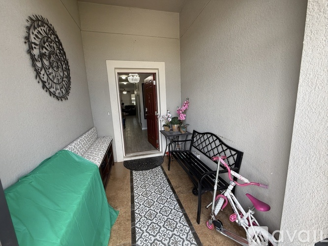A room with a green sofa, a black chair, and a pink bicycle.