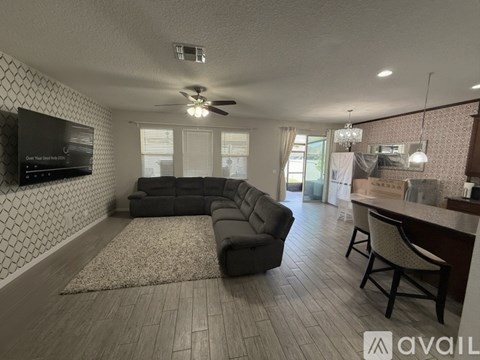 A living room with a black sofa and a television mounted on the wall.