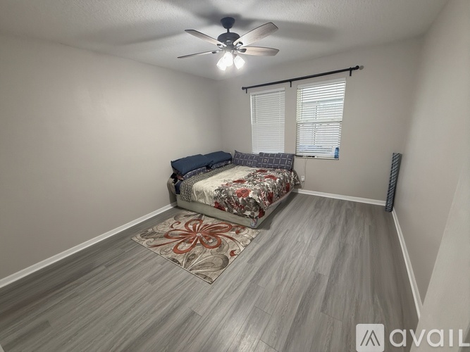 A bedroom with a bed, a ceiling fan, and a rug on the floor.
