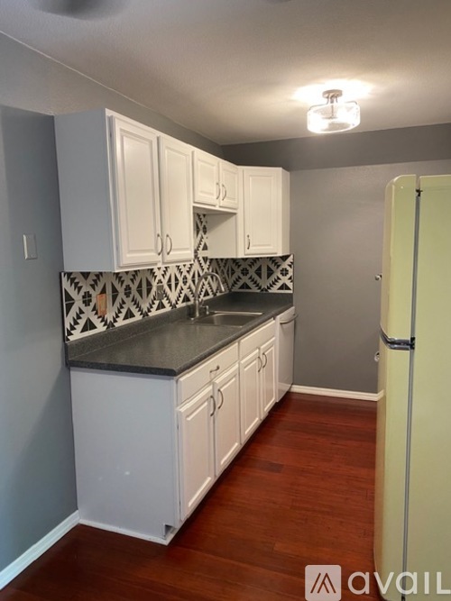 A kitchen with white cabinets and a black and white tile backsplash.