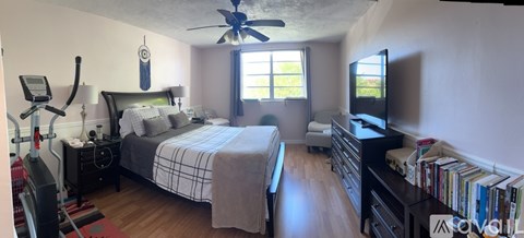 A bedroom with a bed, a television, and a fan.