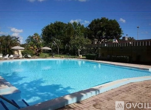 A large swimming pool surrounded by trees and lounge chairs.