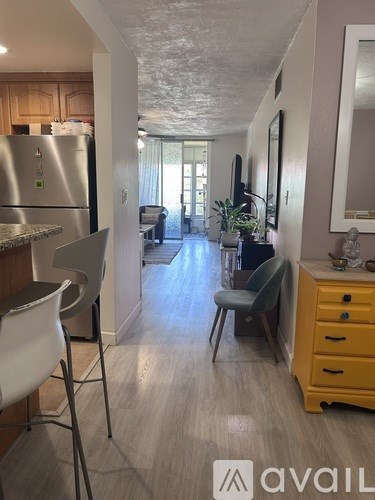 A kitchen with a refrigerator, a dining table with chairs, and a yellow cabinet.